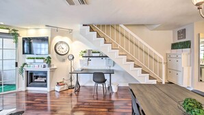 A modern interior with a staircase, a fireplace, a desk, and a dining area.