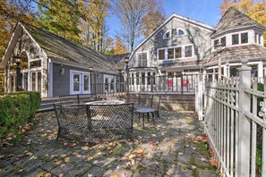 A courtyard with a stone patio, metal chairs, and a small round table.
