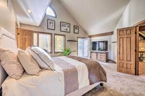 A bedroom with a large bed, a TV, and a staircase leading to a loft area.