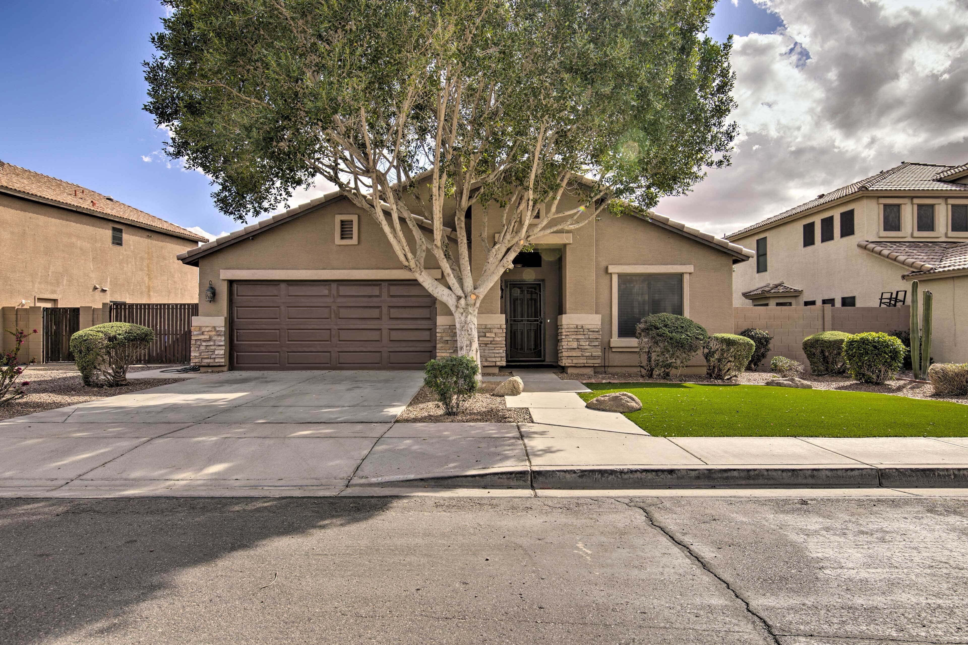 A residential house with a garage, a driveway, a lawn, and a tree.