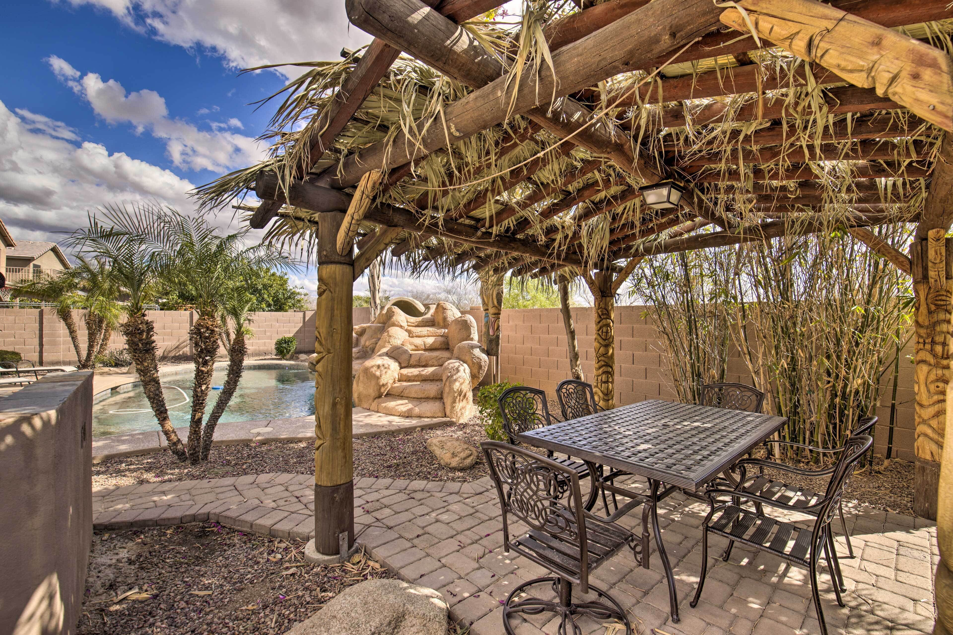 Un espace extérieur aménagé avec une terrasse, une pergola, une piscine et une table entourée de chaises.