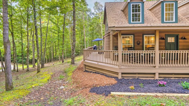 Une cabane à deux étages avec une terrasse, entourée d’une forêt.