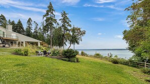 A house with a large lawn, a deck, and a view of the water. - Hike, Bike & Explore: Oceanfront Kingston Getaway (Kingston)