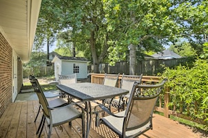 Un patio exterior con una mesa y sillas, rodeado por una terraza de madera y una valla de madera.