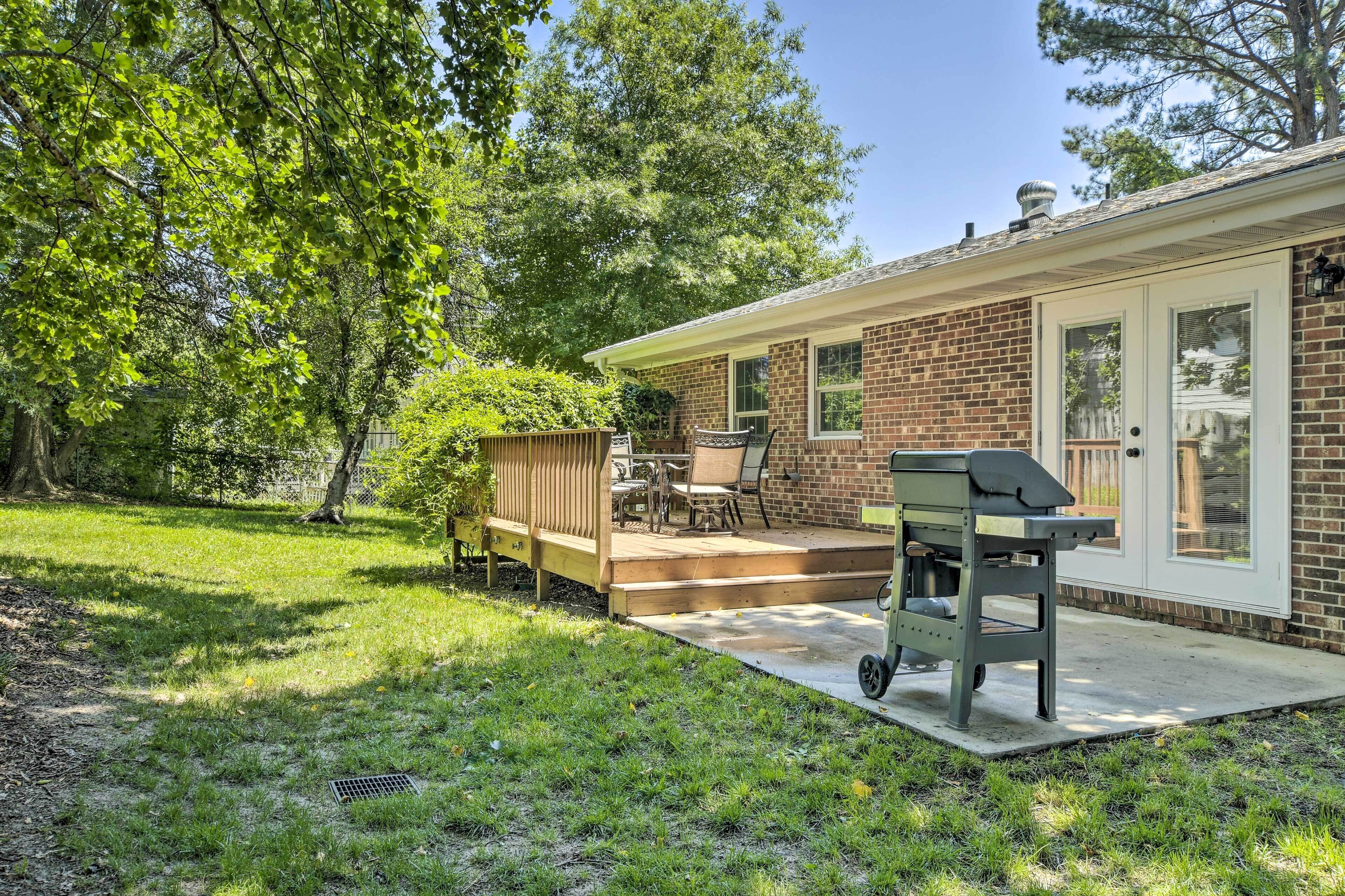 A backyard with a patio, a grill, and a covered seating area.