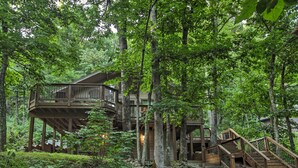 A wooden cabin with a multi-level deck surrounded by dense forest. - Cozy 'hillside Hideaway' in Wintergreen Resort! (Roseland)