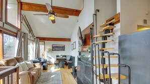 A spacious living room with a wooden ceiling, a large window, a sofa, a dining table, and a staircase with wooden steps. - Cozy 'hillside Hideaway' in Wintergreen Resort! (Roseland)