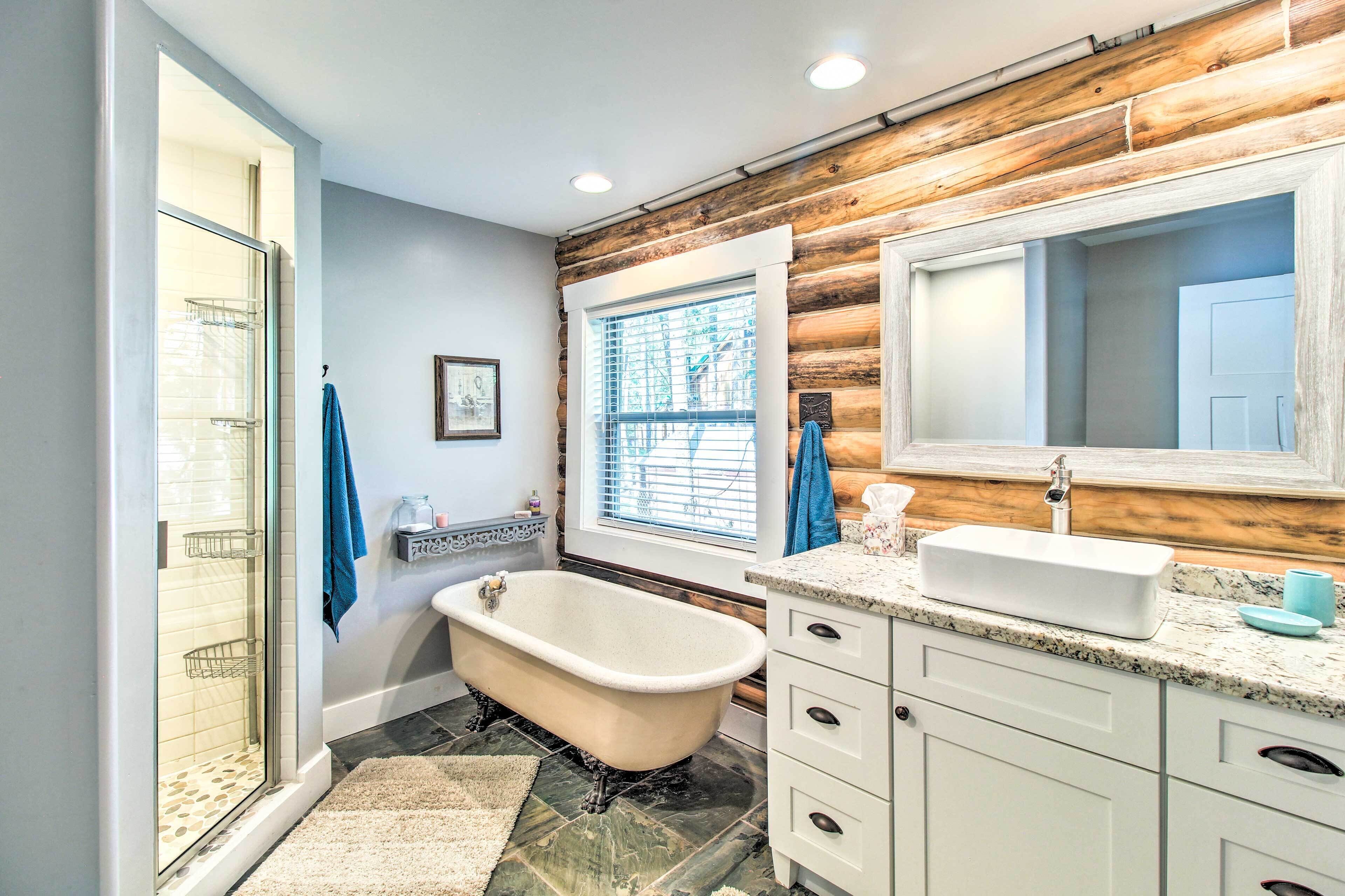 A bathroom with a freestanding bathtub, a large mirror, a sink, and a shower enclosure.