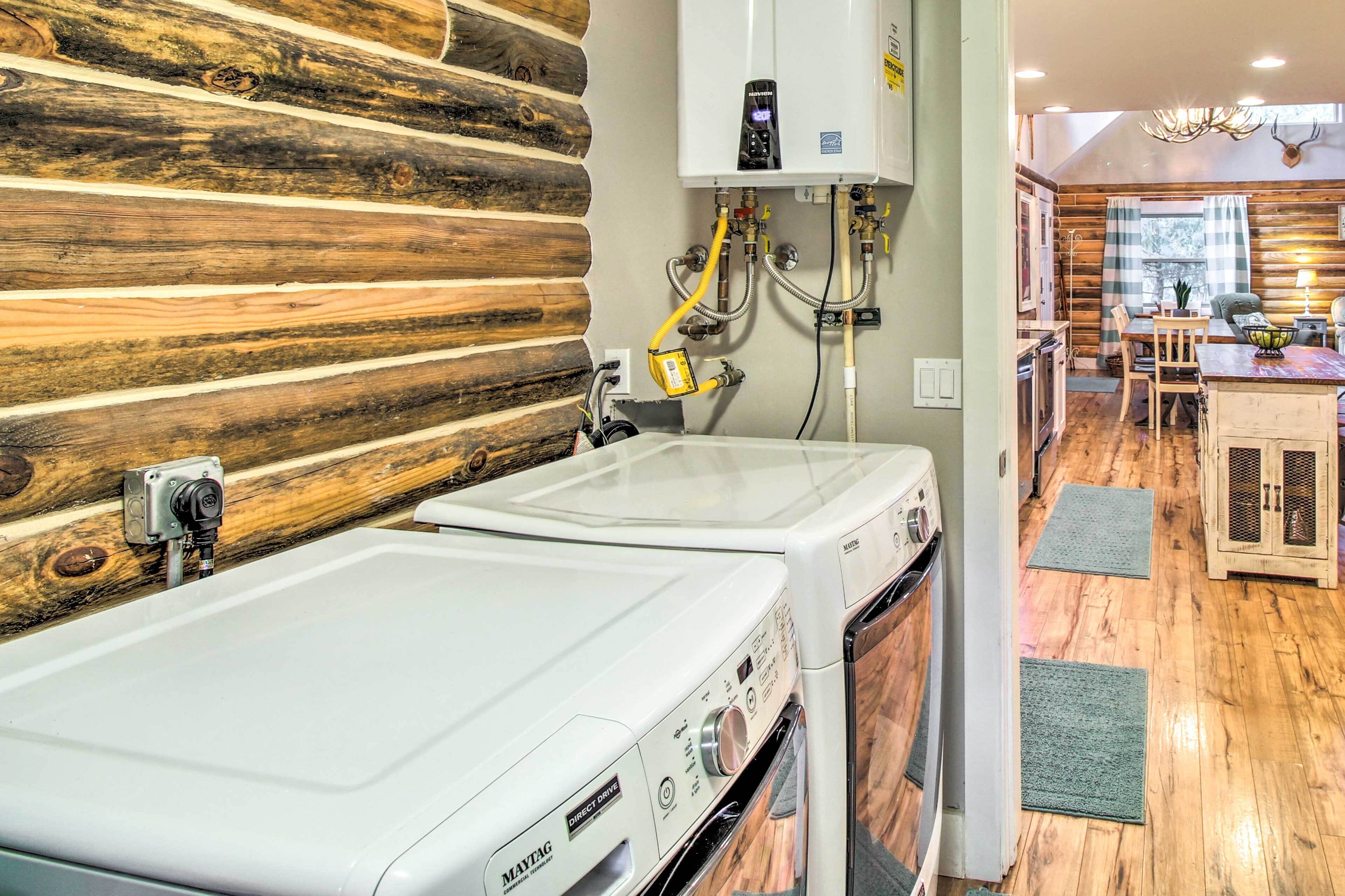 A laundry area with two Maytag washers, a wooden wall, and a kitchen area in the background.