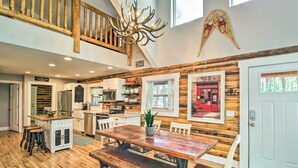 A spacious kitchen with wooden accents, a dining area with a large wooden table, and a staircase with a unique antler chandelier. - 1 Mi to Lake: Chic Arizona Cabin w/ Large Porch! (Lakeside)