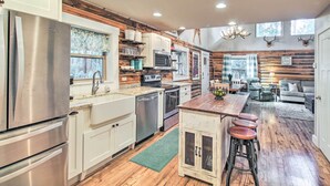 A modern kitchen with stainless steel appliances, wooden accents, and a central island with bar stools. - 1 Mi to Lake: Chic Arizona Cabin w/ Large Porch! (Lakeside)