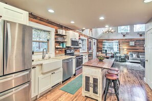 Een moderne keuken met roestvrijstalen apparatuur, houten details en een centraal kookeiland met barstoelen.
