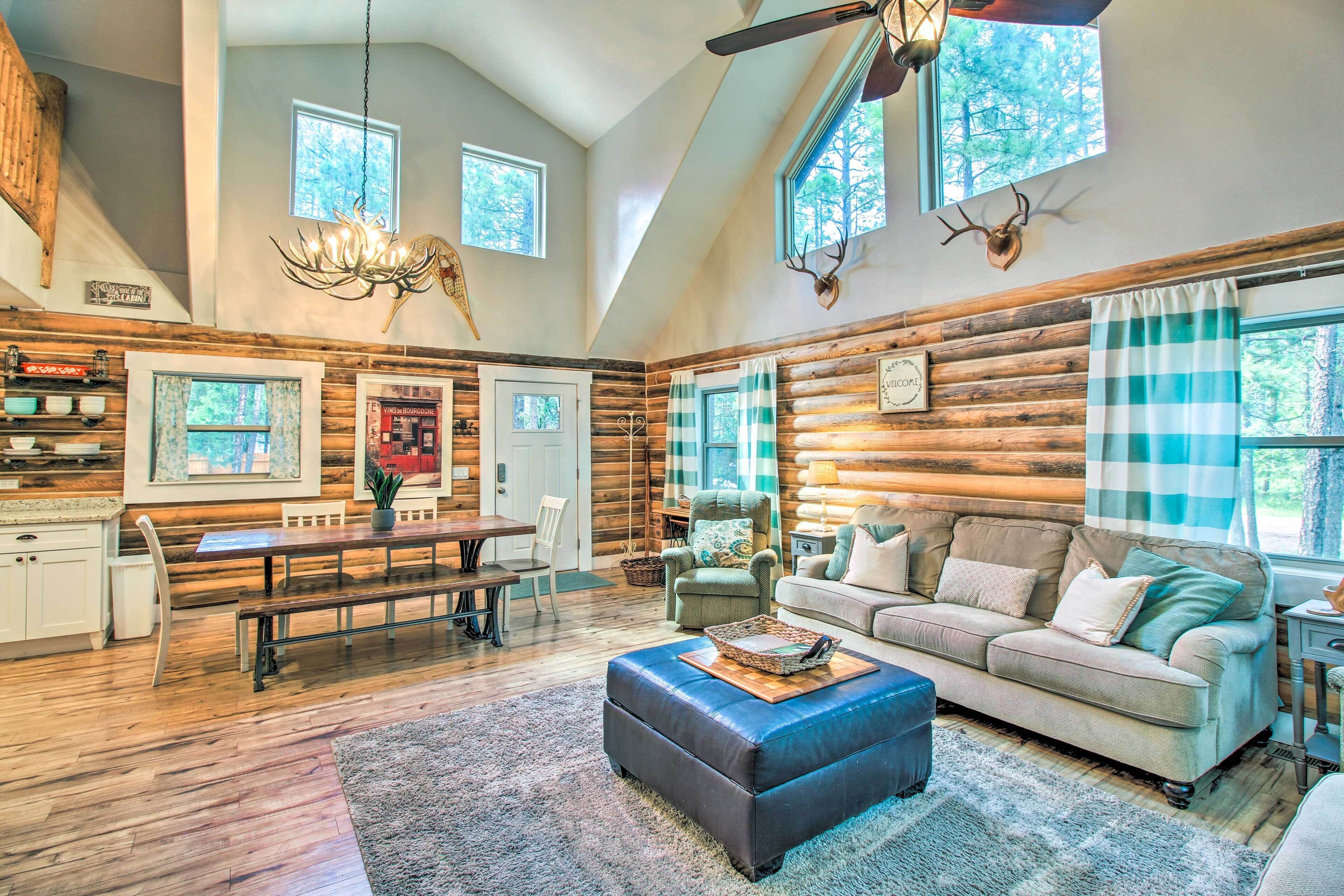 A spacious log cabin interior with a dining area, a sofa, and a chandelier.