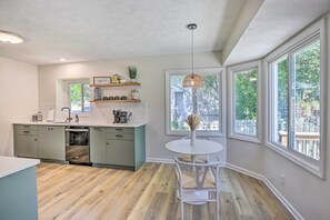 A kitchen with a central island, built-in appliances, and a dining area with a round table and chairs. - Modern Boho Gem: Yard + 10 Mi to Baxter Arena (Omaha)
