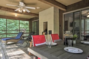 A covered outdoor dining area with wicker lounge chairs, red and black chairs, a table set for two, and a ceiling fan. - Mountain Town Adventures Home w/ Fire Pit! (Fort Valley)