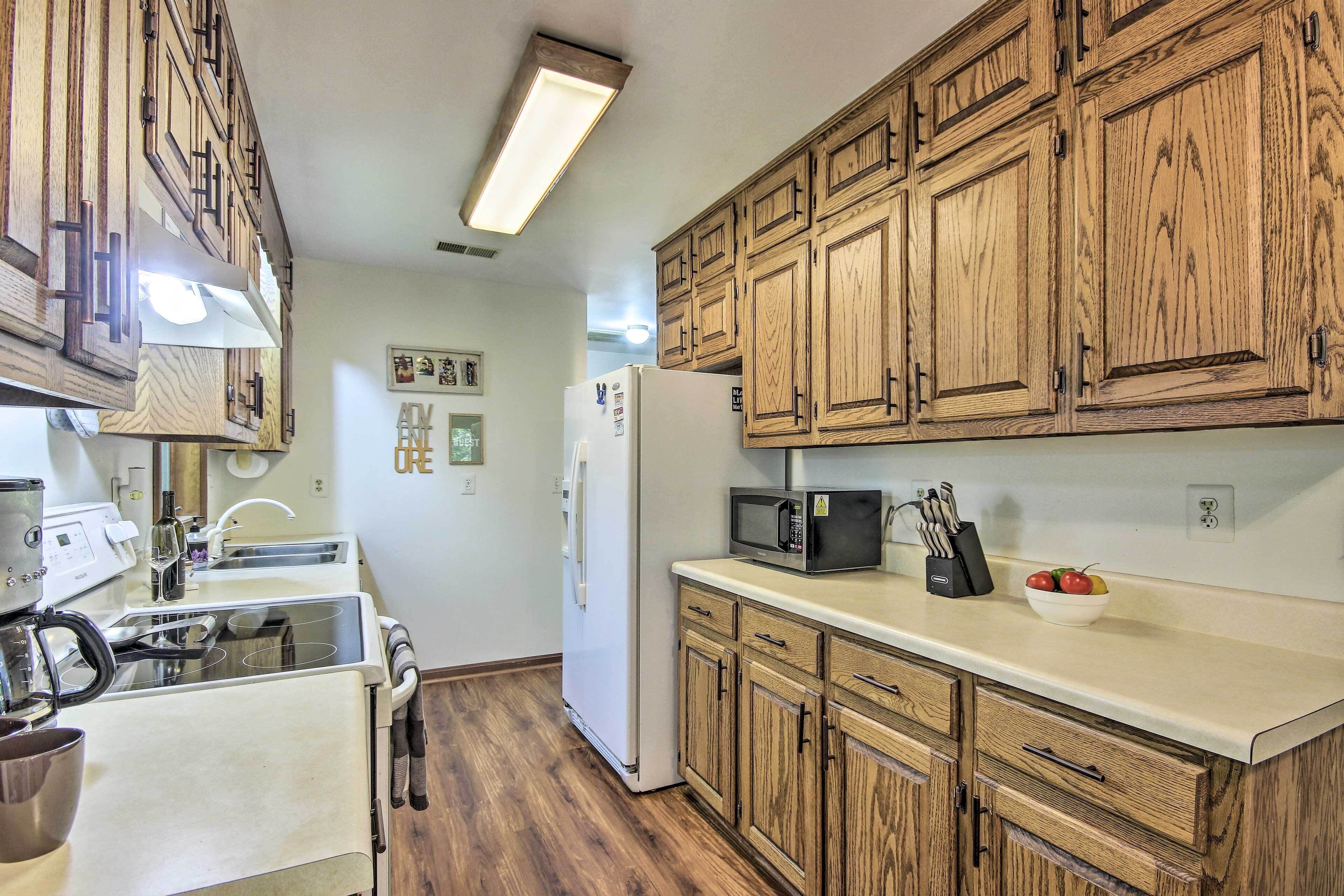 A kitchen with wooden cabinets, a refrigerator, a microwave, and a sink.