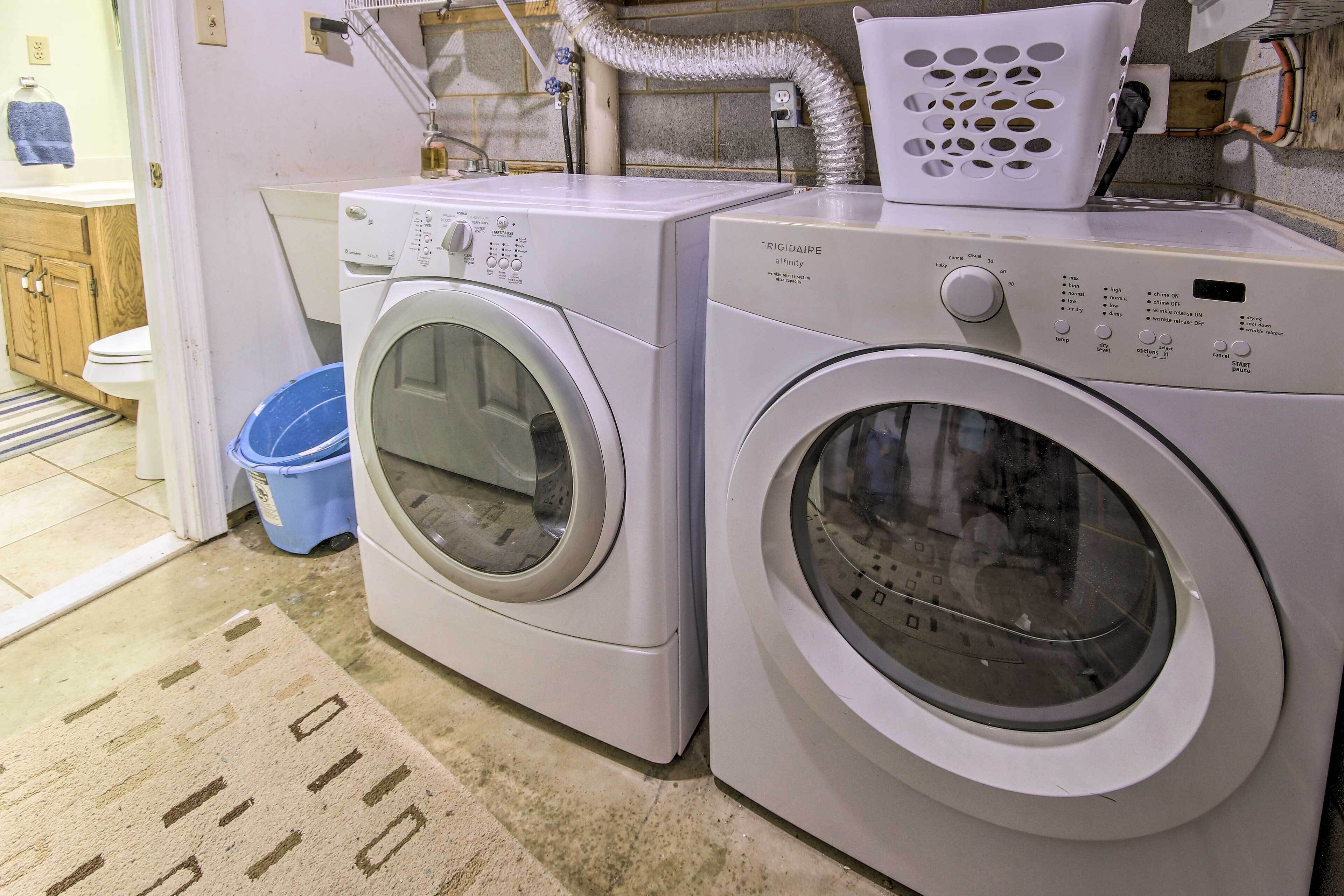 A laundry area with two front-loading washing machines, a blue bucket, and a white laundry basket.