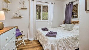 A bedroom with a bed, a dresser, a window with curtains, and a view of trees. - Mountain Town Adventures Home w/ Fire Pit! (Fort Valley)