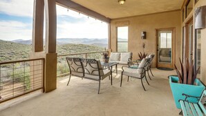 A covered patio with a table and chairs, a sofa, and a view of the mountains. - Mtn-view Adobe Home w/ Large Deck Near Prescott! (Mayer)