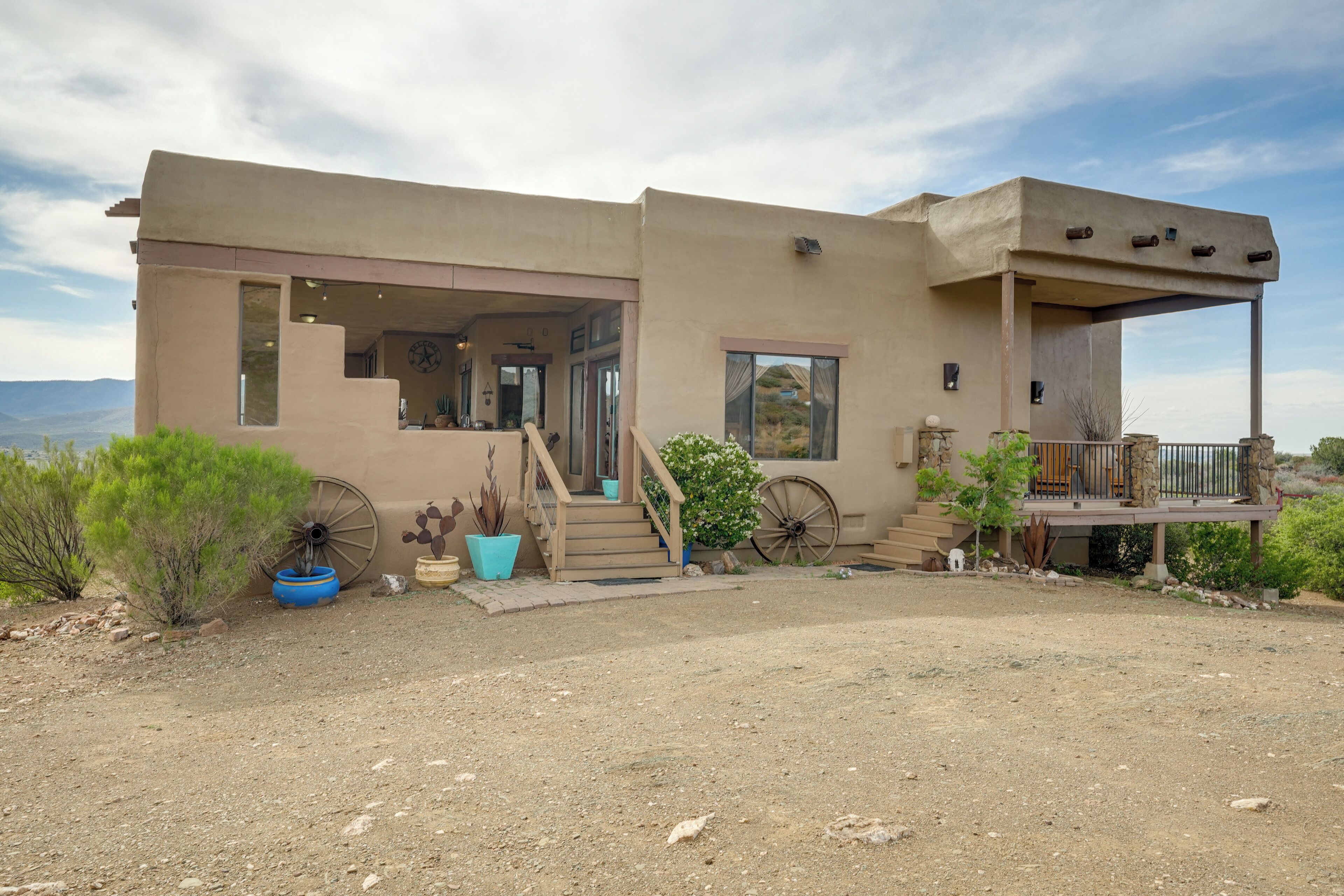 A modern house with a covered porch, a staircase leading to the entrance, and a view of the surrounding landscape.
