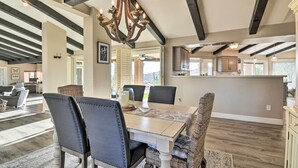 Un comedor amplio con una gran mesa de madera, sillas tapizadas oscuras y una lámpara decorativa.