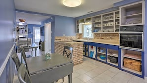 A kitchen with a brick backsplash, white cabinets, and a built-in oven. - Lake Erie Waterfront Home w/ Sunroom & Yard! (Erie)