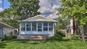 A single-story house with a front porch, a covered patio, and a small front yard. - Lake Erie Waterfront Home w/ Sunroom & Yard! (Erie)