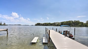 A wooden dock extending into a calm lake with a clear sky.