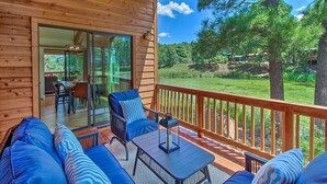 Une terrasse en bois avec des sièges extérieurs et une porte vitrée donnant sur un espace de salle à manger intérieur.