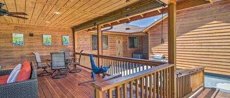 A wooden deck with outdoor furniture, a ceiling fan, and a view of a house.
