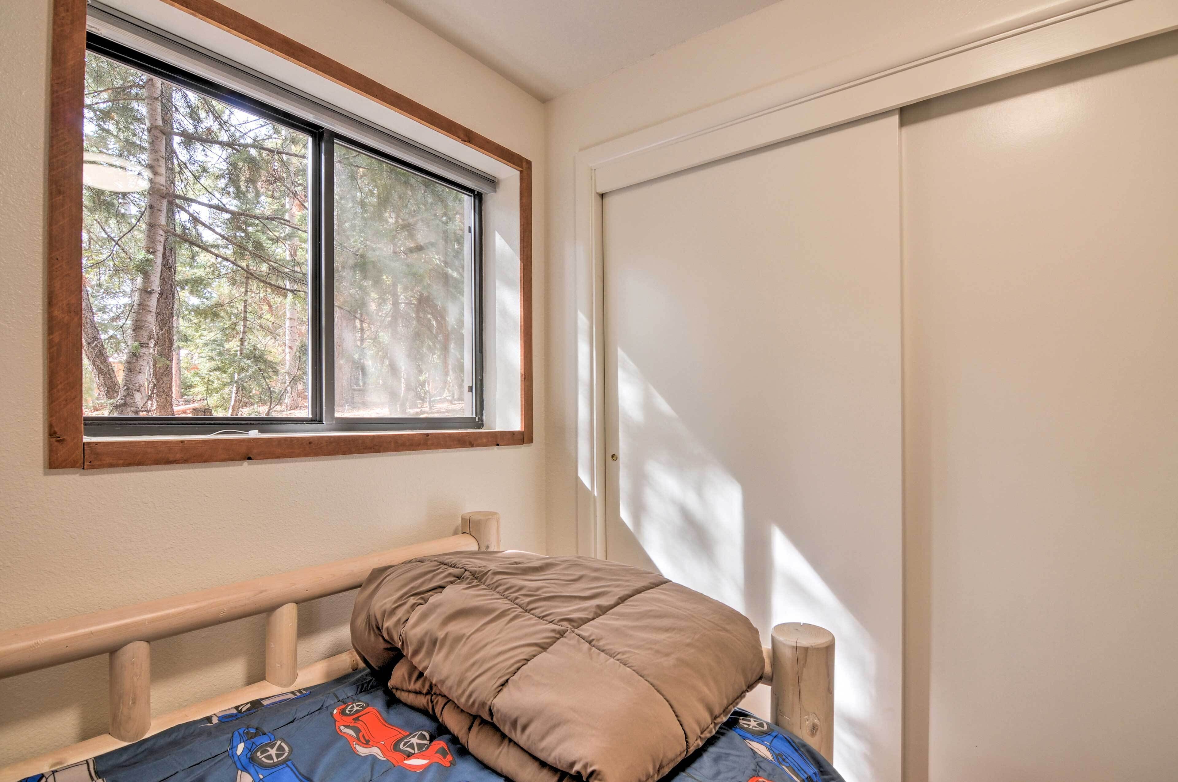 A bedroom with a window, a bed with a blue and red patterned bedspread, and a white door.
