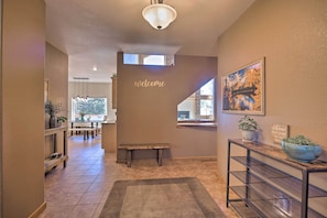 A hallway with a 'welcome' sign, a bench, a console table with a bowl, and a view of a dining area.