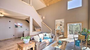 Un vaste salon doté d’un haut plafond, d’un plancher en bois, d’un canapé en cuir, d’une table basse et d’un escalier menant à l’étage supérieur.