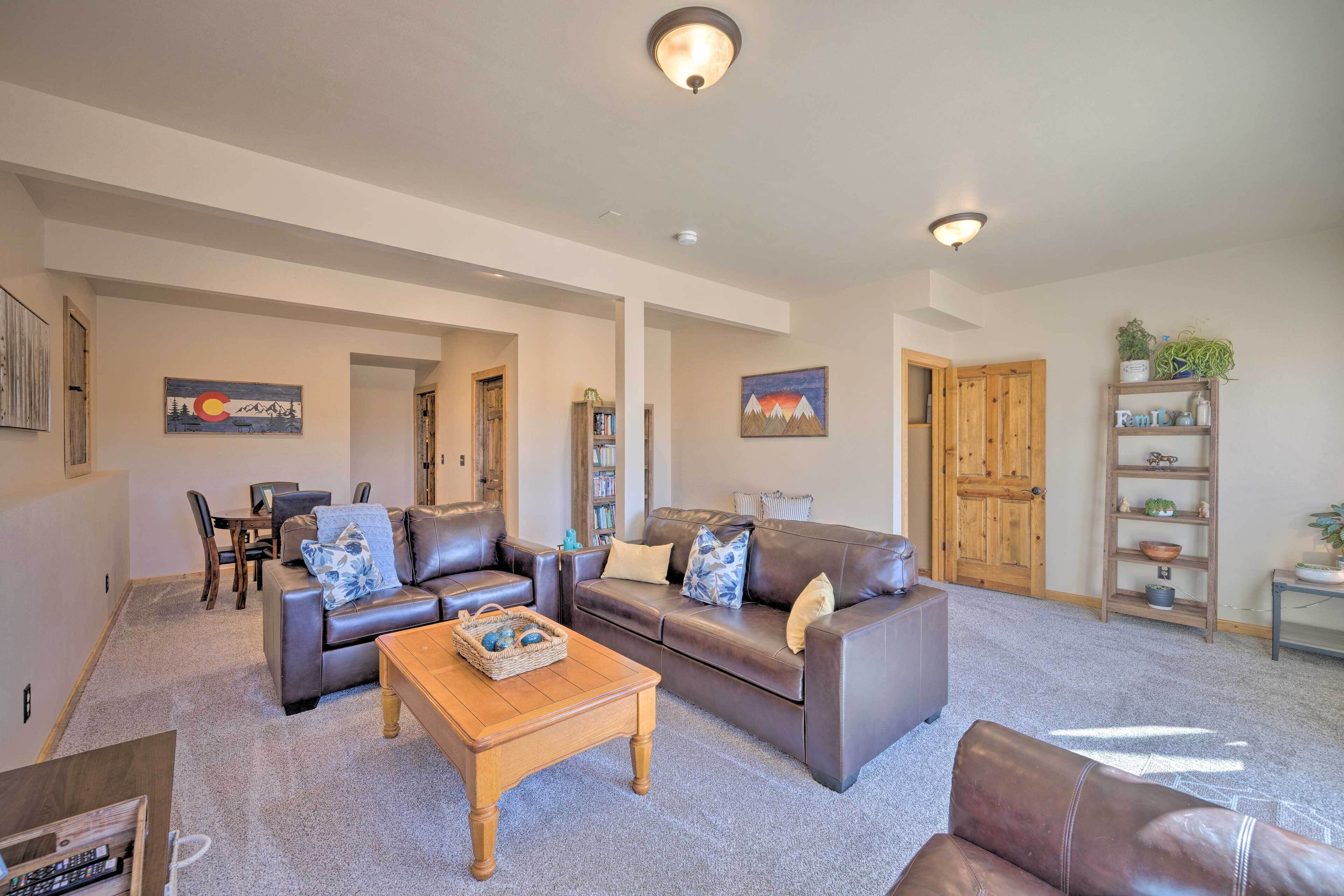 A spacious living room with a brown leather sofa, a wooden coffee table, and a bookshelf.