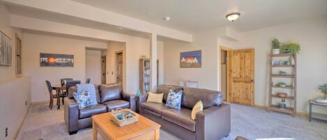 A spacious living room with a brown leather sofa, a wooden coffee table, and a bookshelf.