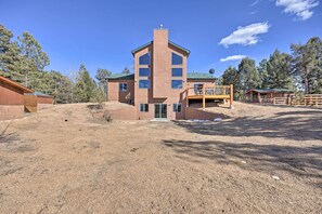 A multi-story building with a central entrance, a covered outdoor area, and a dirt ground.