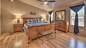 A bedroom with a wooden bed, nightstands, a bench, a ceiling fan, a dresser, and a mirror. - Near Hiking: Munds Park Cabin w/ Deck & Yard (Munds Park)