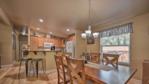 A kitchen with wooden cabinets, a dining table with chairs, and a window with blinds. - Near Hiking: Munds Park Cabin w/ Deck & Yard (Munds Park)