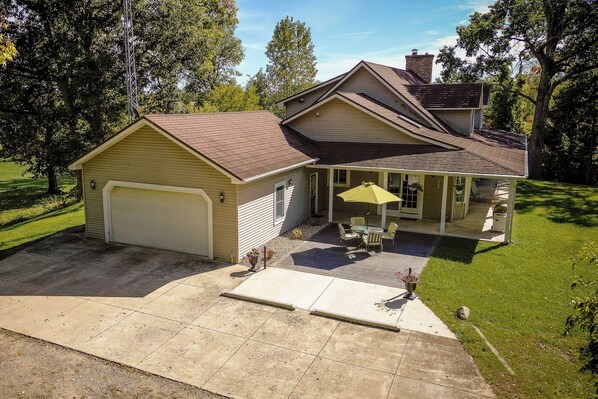 A two-story house with a garage, a covered patio with outdoor furniture, and a well-maintained lawn.