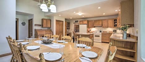 A spacious dining area with a wooden table set for six, surrounded by wooden chairs.