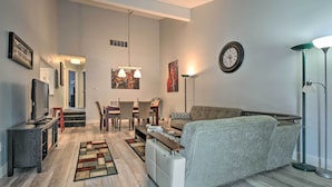 A modern living room with a sofa, coffee table, TV, and dining area.
