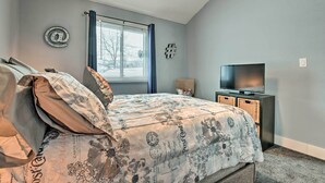 A bedroom with a bed, a television, a window with curtains, and a wall with a decorative symbol.