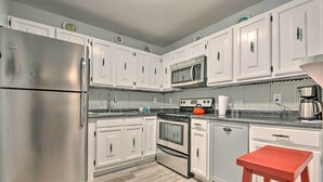 A modern kitchen with white cabinets, stainless steel appliances, and a wooden floor.