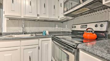 A kitchen with white cabinets, a black stove, and a microwave.