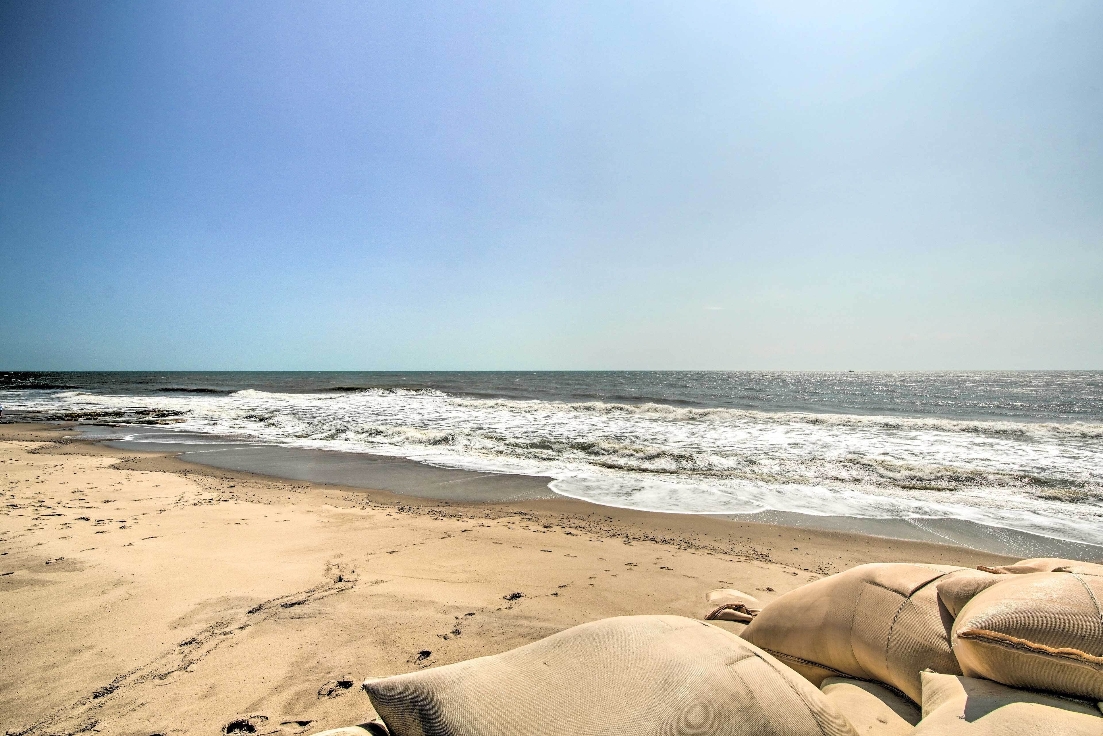 Una spiaggia con sabbia e onde, e una persona sdraiata su un asciugamano.