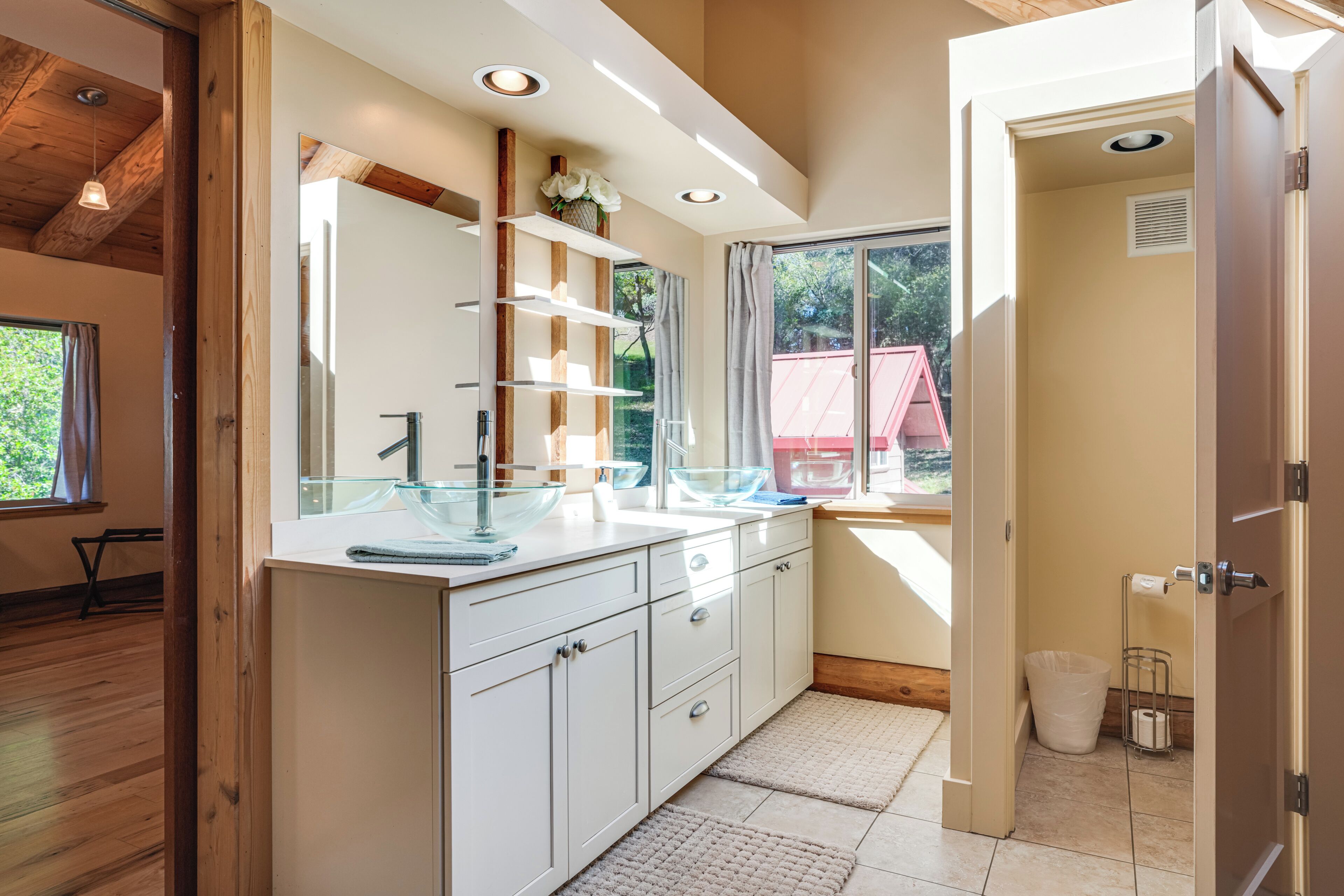 A modern kitchen with white cabinets, a glass bowl on the counter, and a window with curtains.