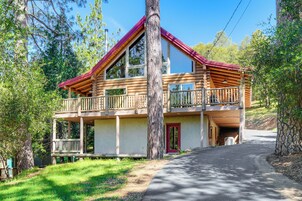 A two-story log cabin with a balcony, a garage, and a driveway leading to the entrance.