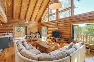A log cabin interior with a large sofa, dining table, TV, and wooden floors.