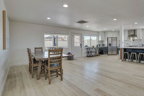 A spacious kitchen with a dining area, wooden chairs, a refrigerator, and a tiled backsplash.