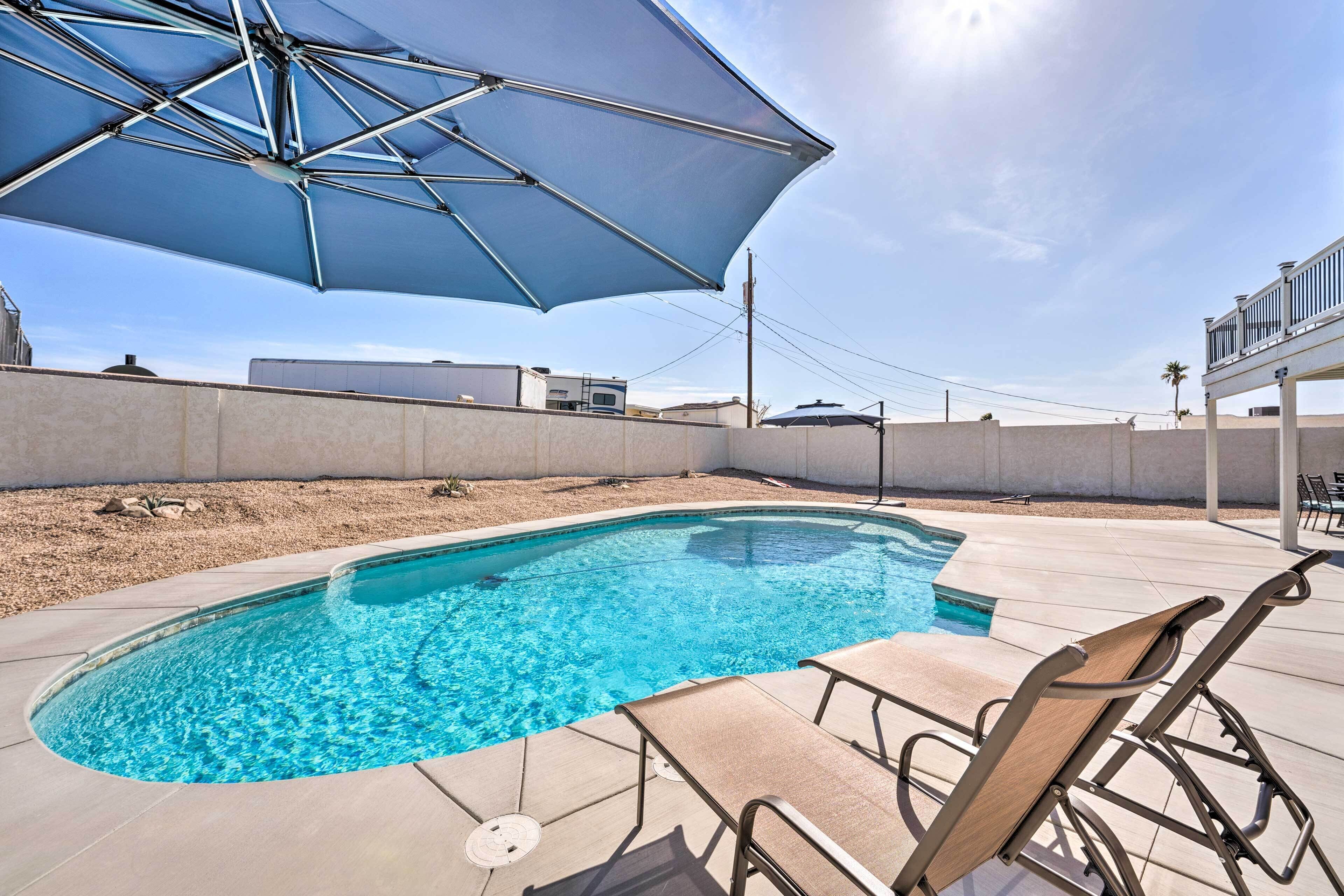 A swimming pool with lounge chairs and an umbrella.